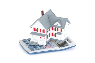 Miniature house with a calculator against a white background